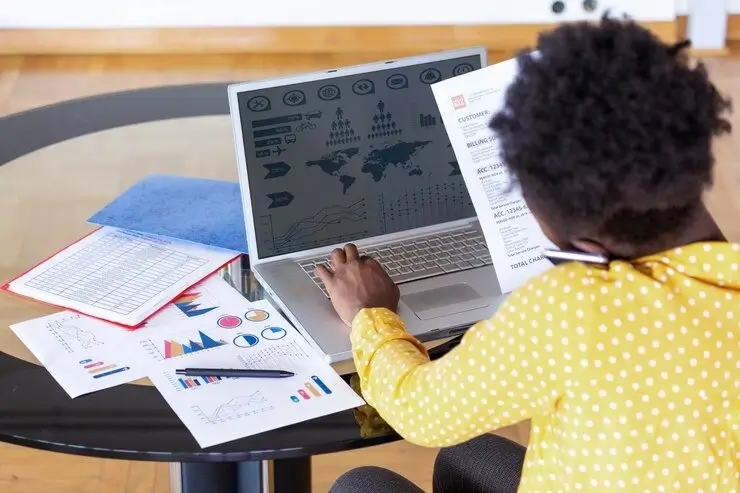 Business woman analyzing data using computer while spending time office